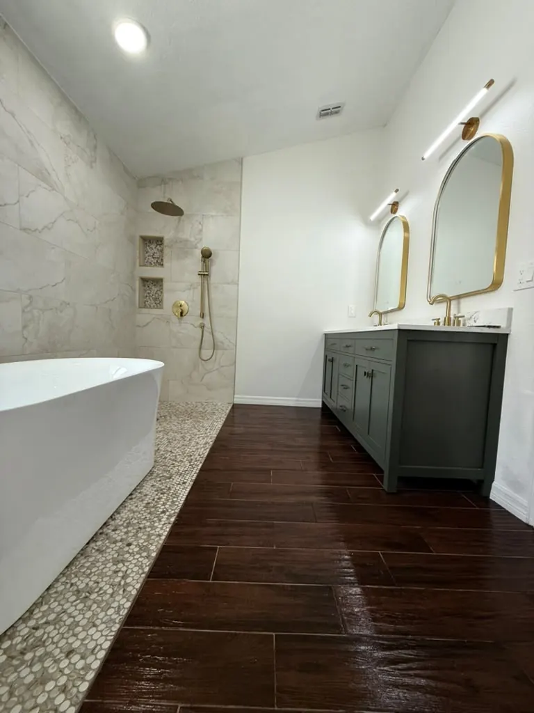 Baño principal con ducha a nivel sin reborde, porcelanato símil mármol, tina exenta y doble mueble verde con grifería de bronce