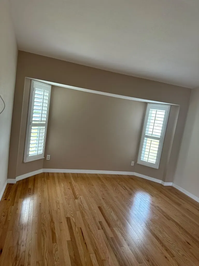 Finished room with natural oak flooring, plantation shutters and an accent wall