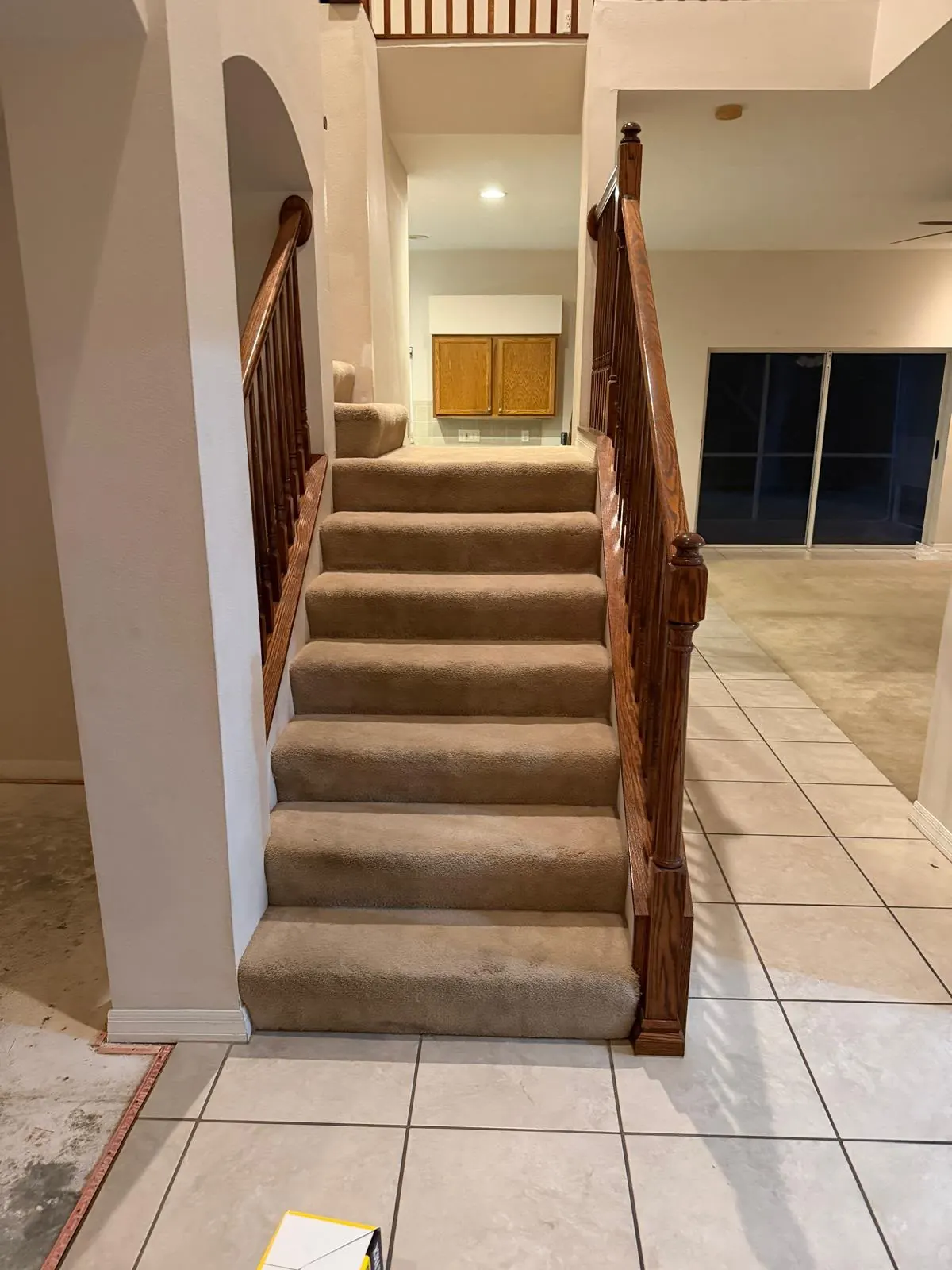 Staircase with beige carpet and dated oak railing before remodeling